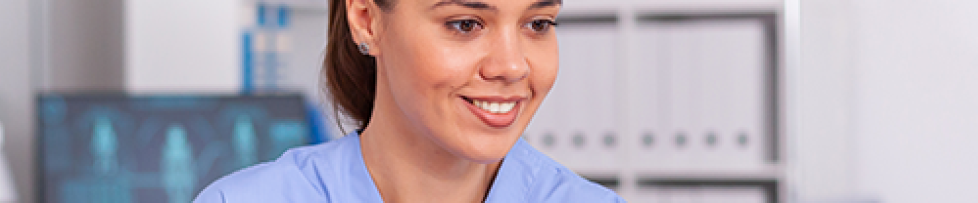 Woman in Scrubs Using a Laptop at a Desk