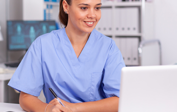 Woman in Scrubs Using a Laptop at a Desk
